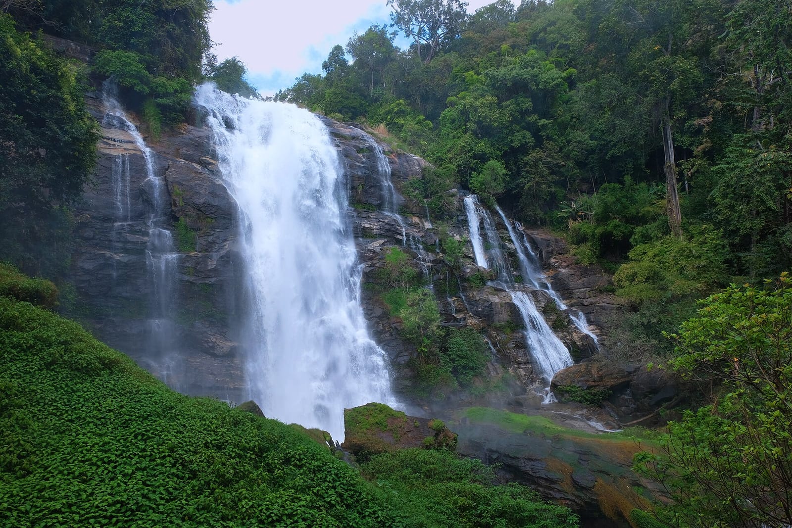 Wachirathan waterfall plunging in a single wide curtain into a rocky pool
