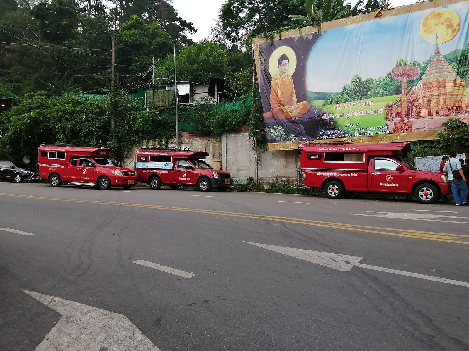 Red songthaew shared taxis queued on the road below Wat Phra That Doi Suthep