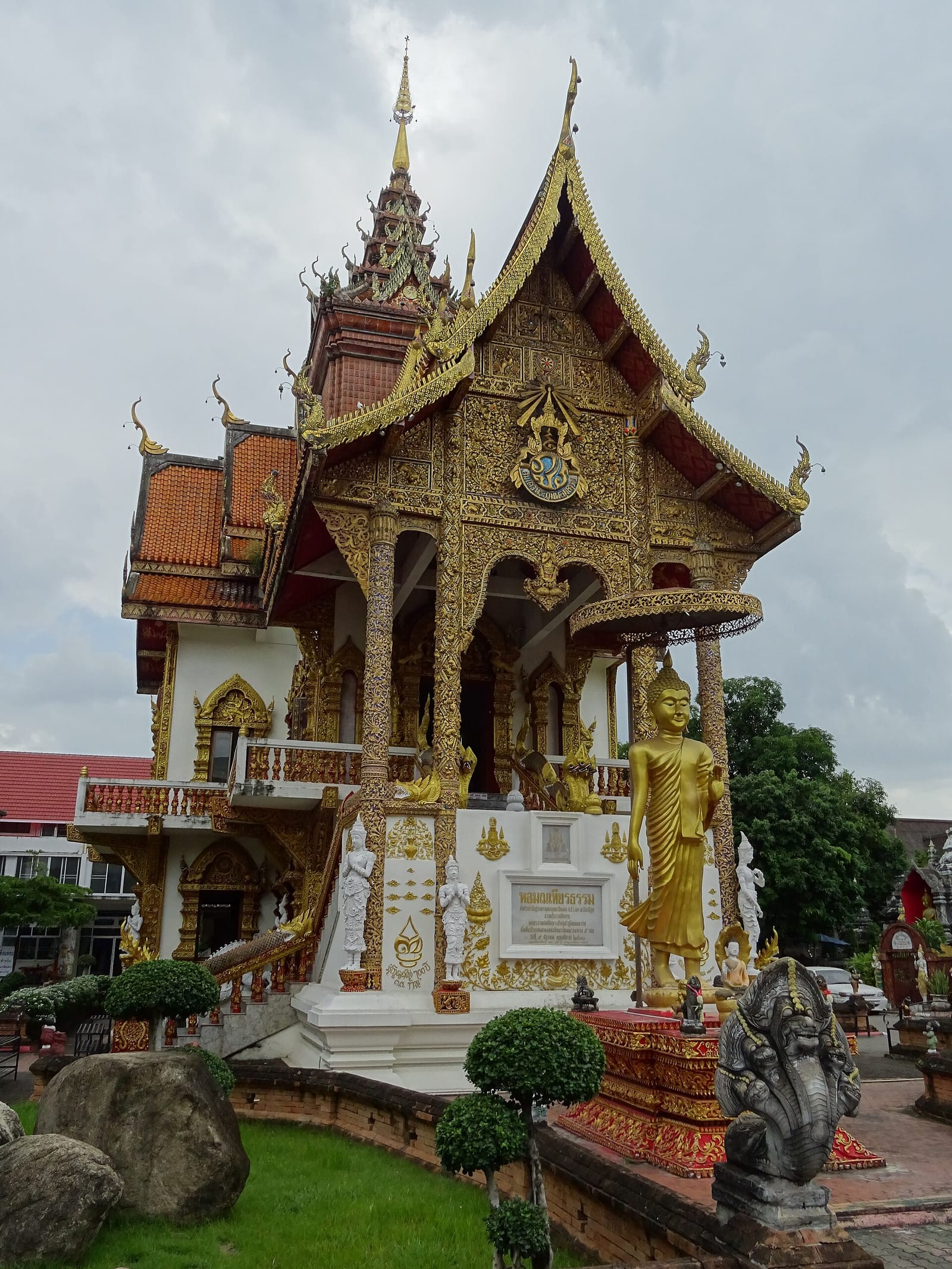 Modern hall added in the late 20th century, in white and gold with ornate gilded gables and a standing Buddha at the entrance