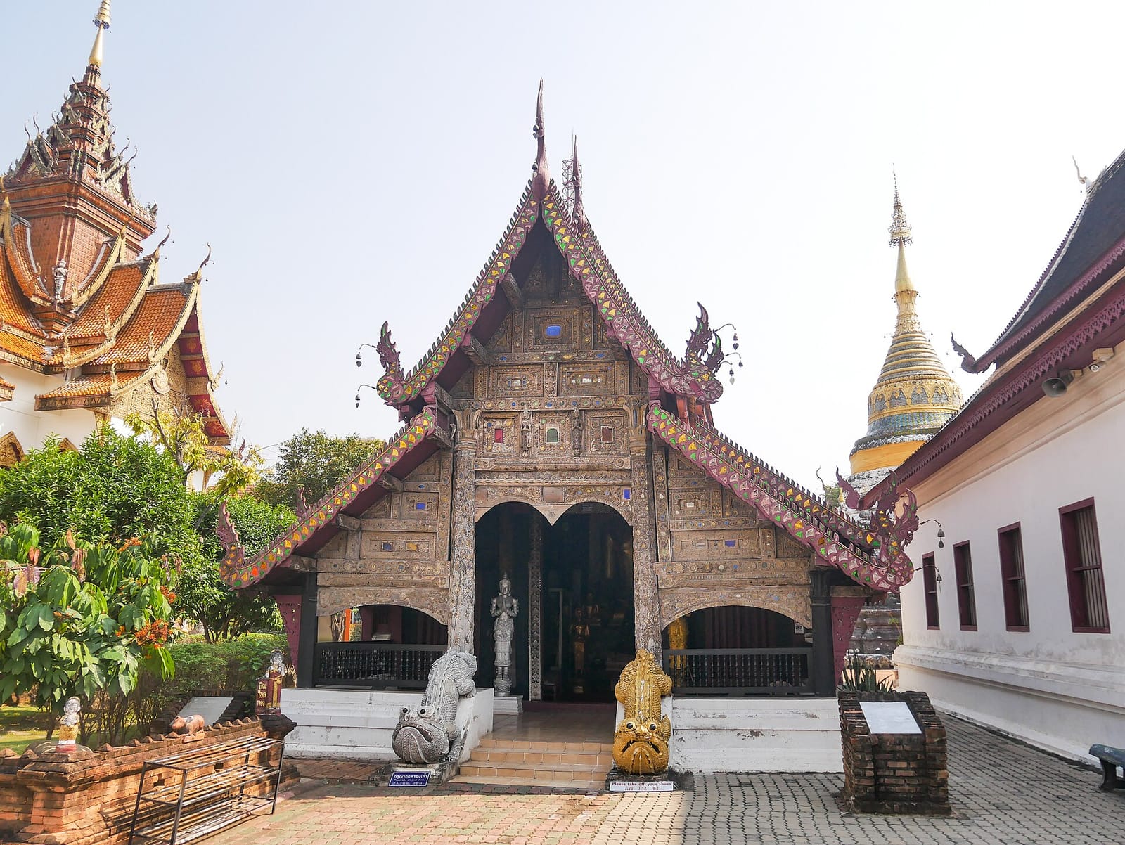 The old teak viharn with its carved and inlaid gable and tiered Lanna roof