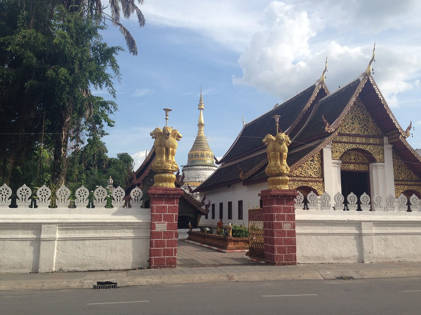 Entrance gate from Tha Pae Road with gilded figures on the gate pillars and the white chedi rising behind