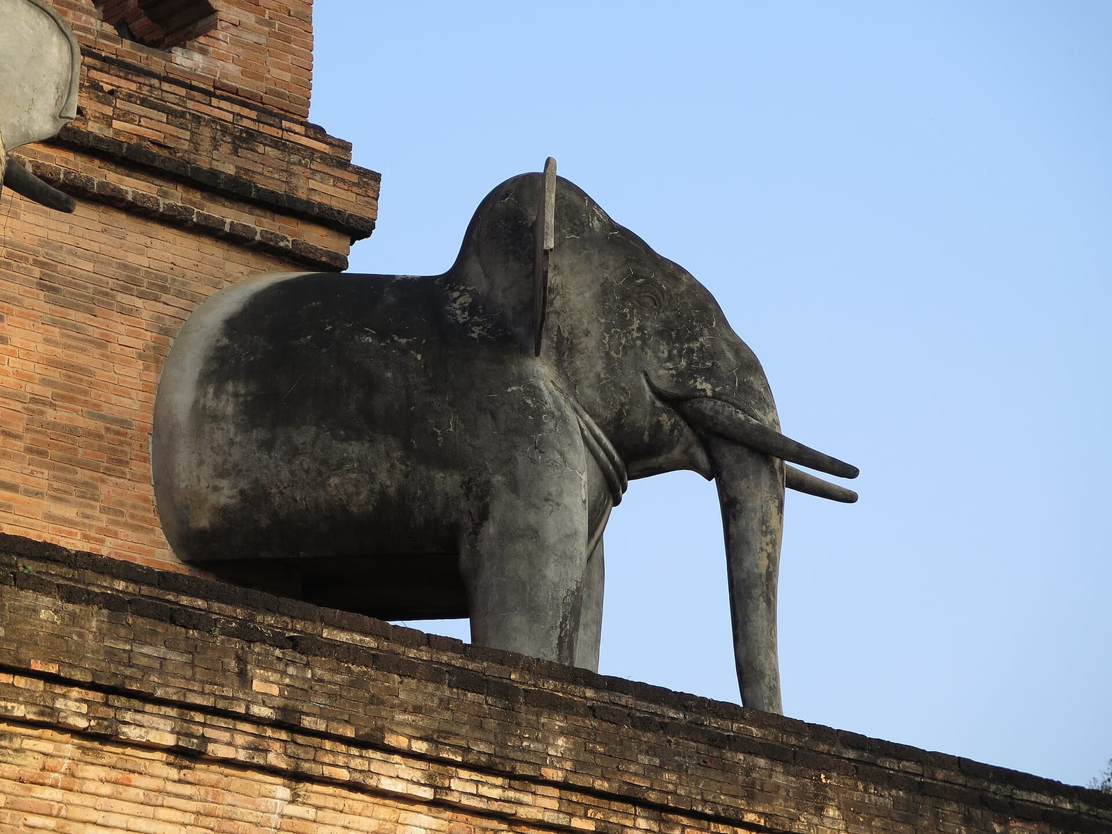 A restored elephant figure on the chedi platform, one of the row replaced in the 1990s after earthquake damage