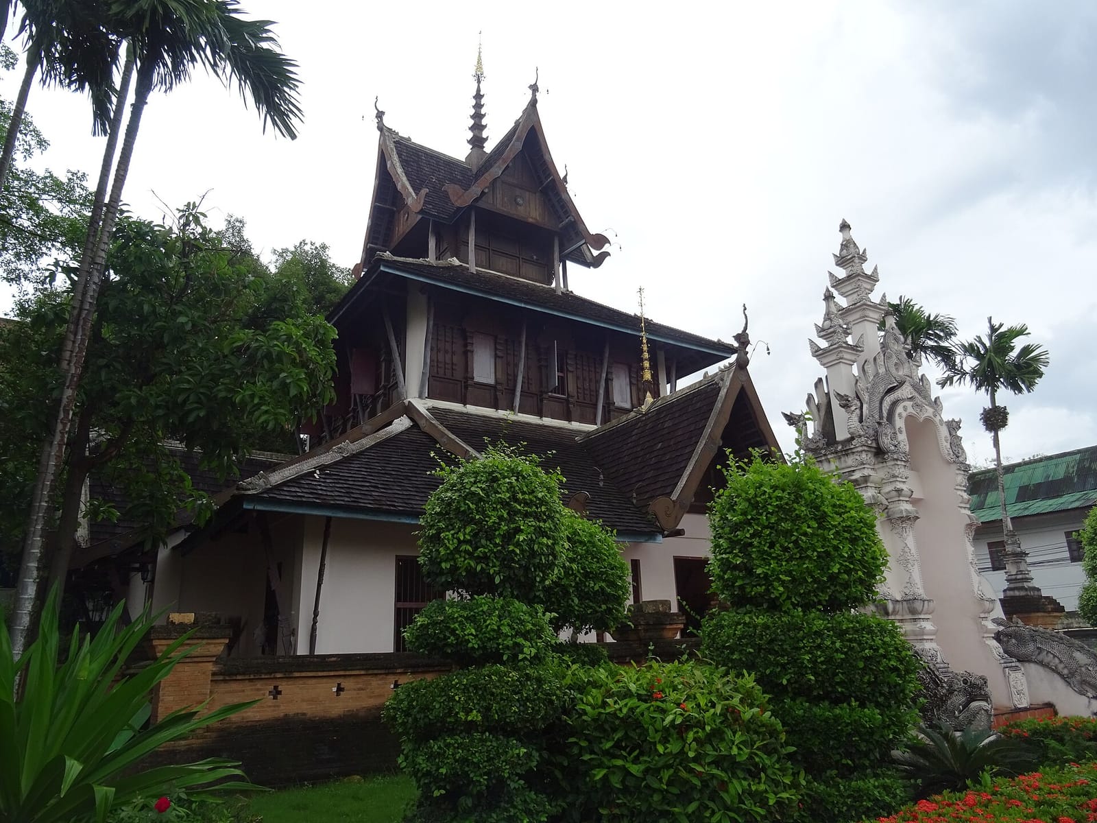 The teak upper storey of the ho trai scripture library rising above its white masonry base at the north of the compound