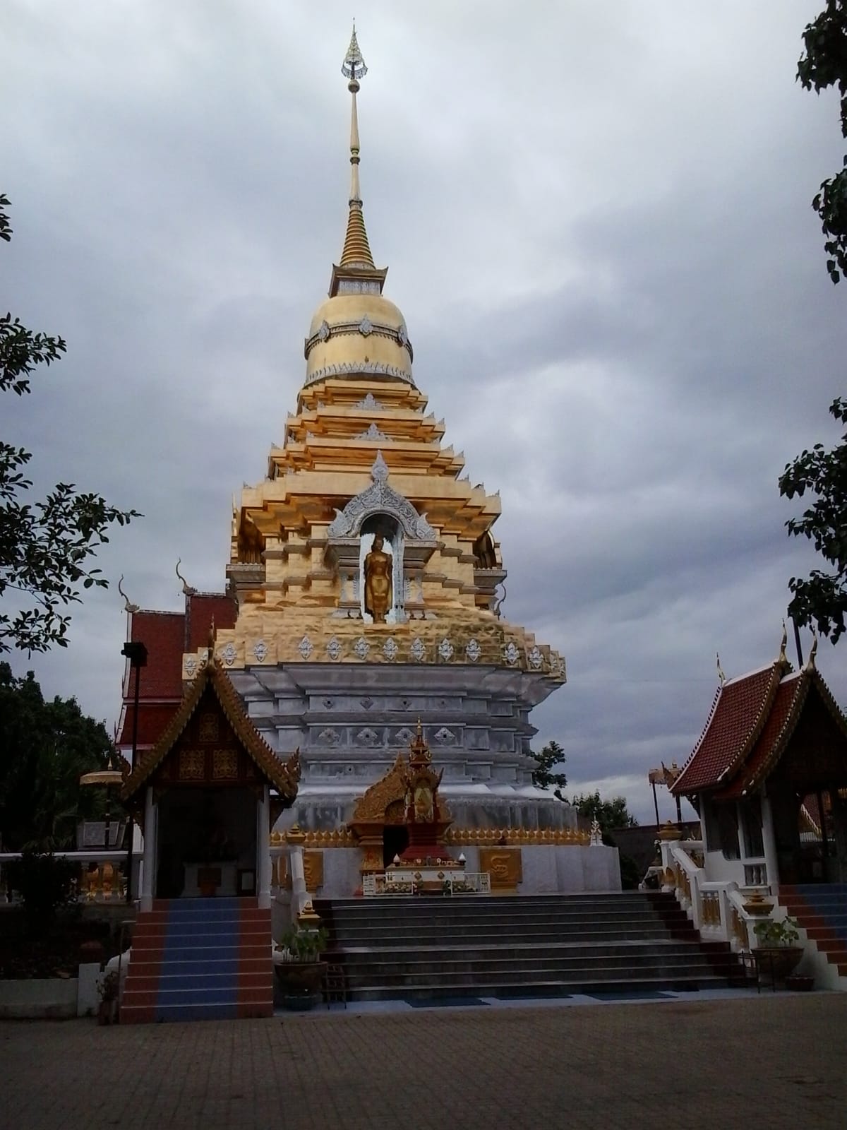 The principal chedi at the top of the hill, gilded upper tiers above a silver-tiled base