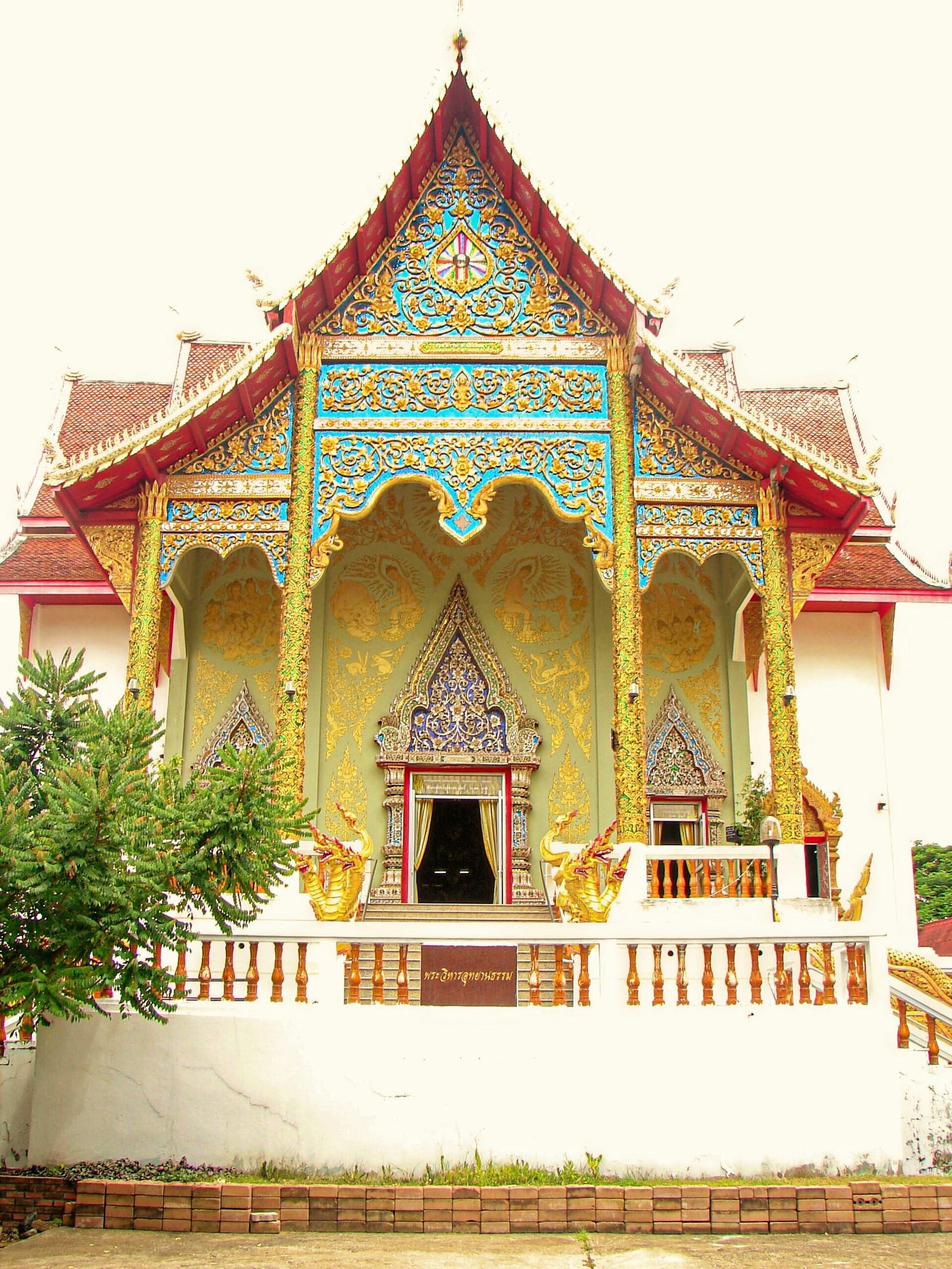 Main viharn of Wat Doi Saket with tiered Lanna roof and gilded gable carving above the entrance porch