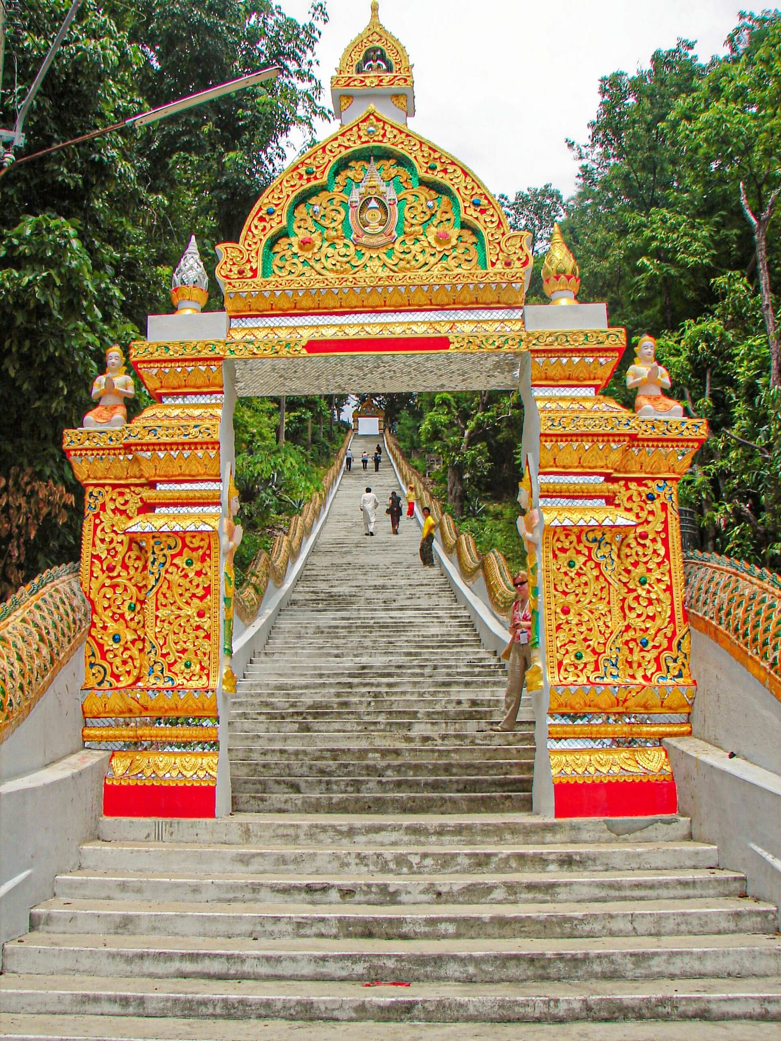 The naga balustrades and 309-step staircase rising beyond the ornate entrance gate at the foot of the temple hill