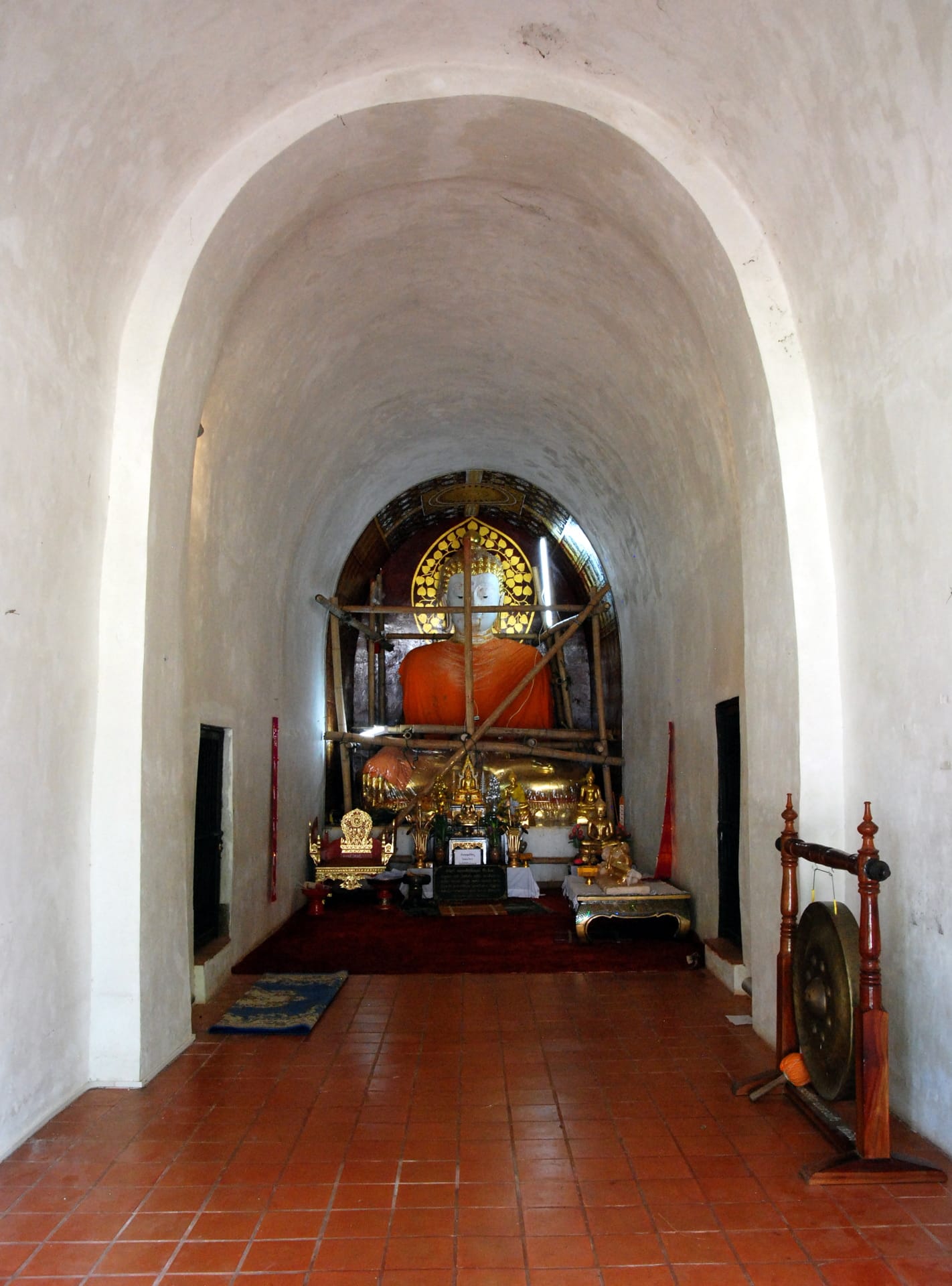 Interior chamber at the base of the chedi holding a seated Buddha image in an orange robe