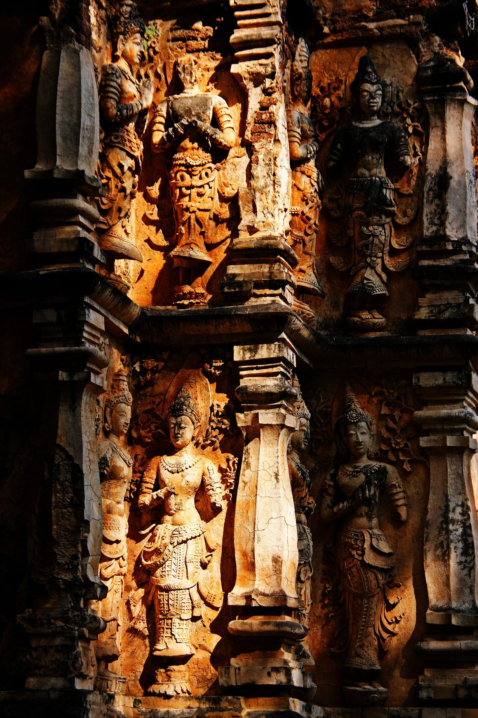 Close detail of the stucco devata reliefs in raking light, showing finely modelled crowns and jewellery