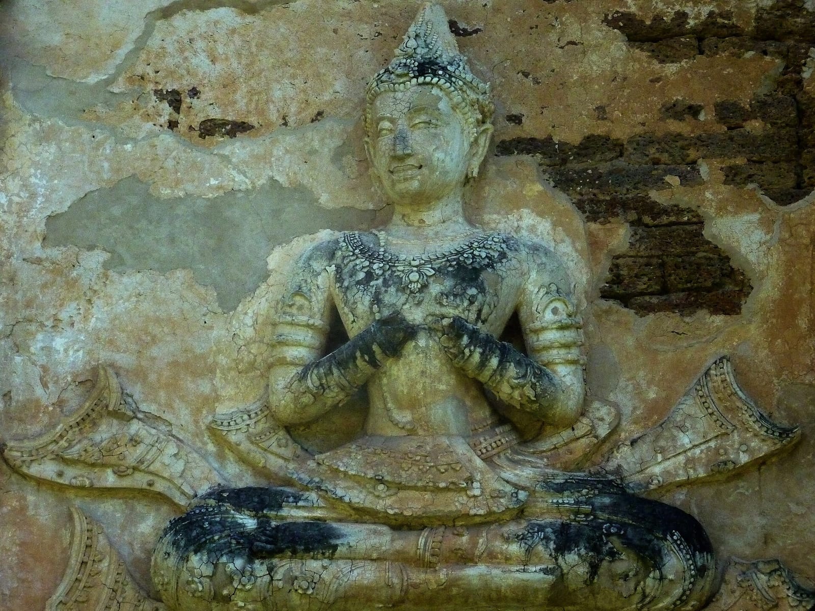 Stucco devata relief on the exterior wall of the chedi, depicting a member of the royal Tilokaraj family