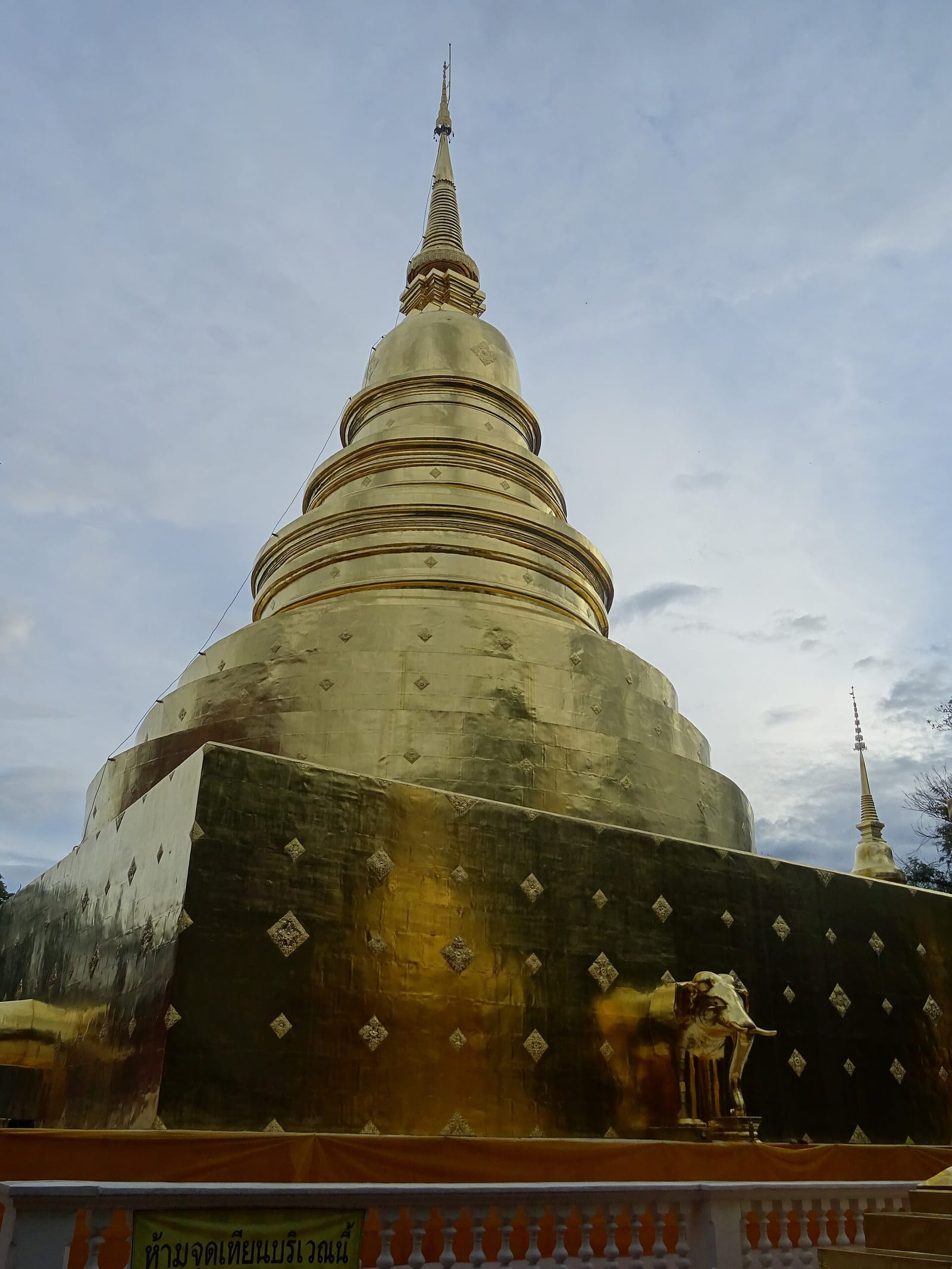 The large bell-shaped chedi behind the principal viharn, with an elephant buttress emerging from its gilded base
