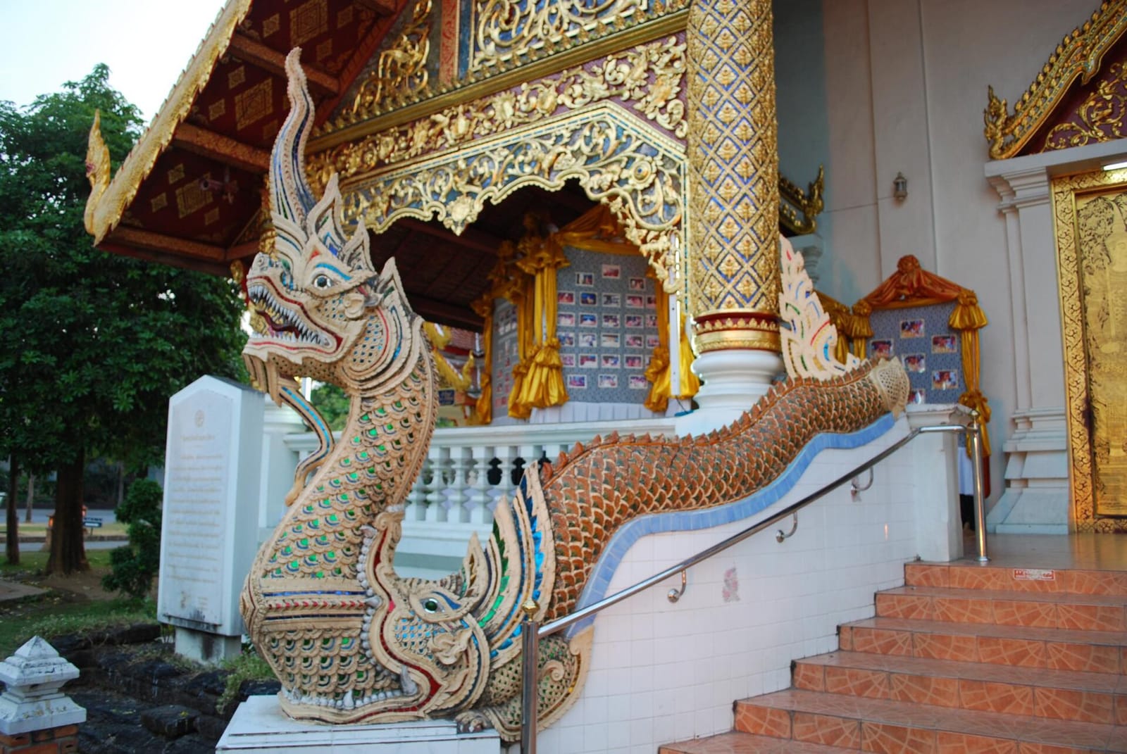 Naga balustrade flanking the entrance to the main viharn, painted gold and inlaid with mirror glass