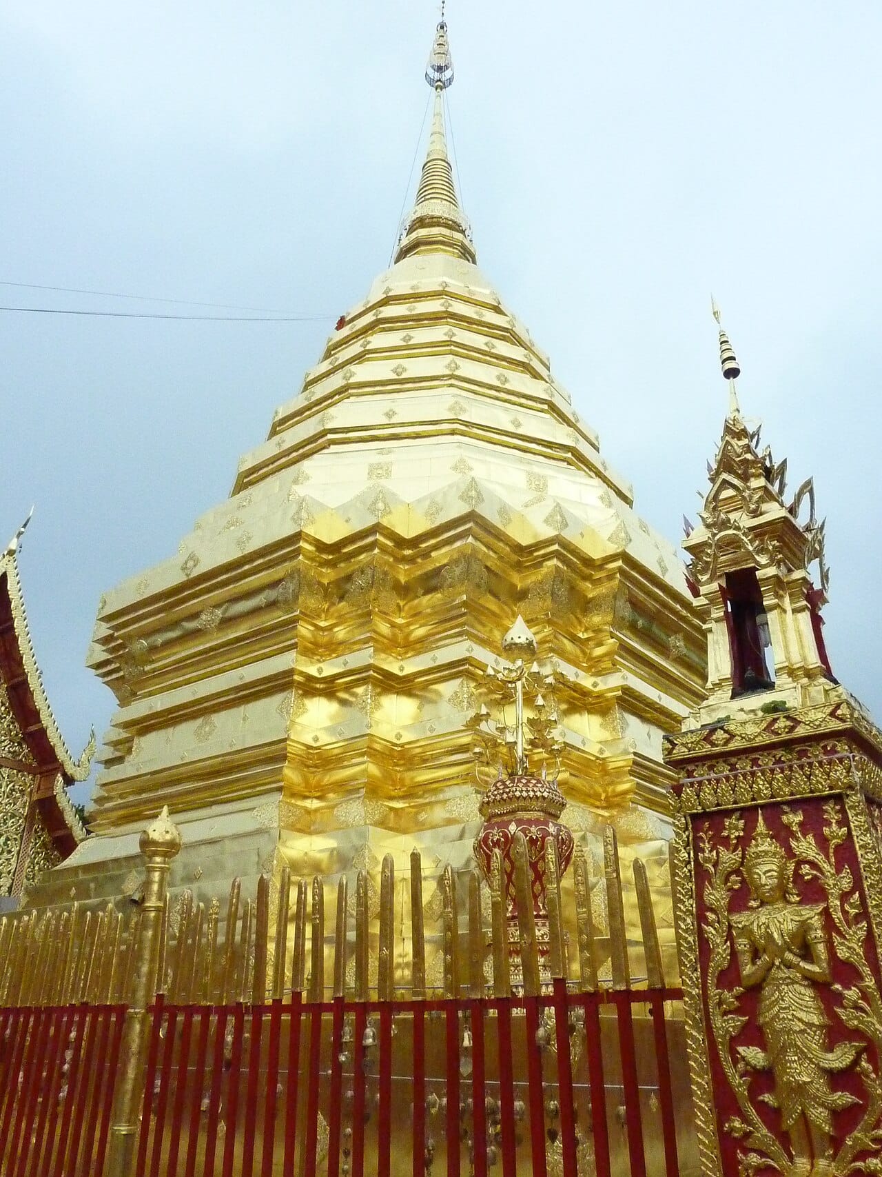 The gilded Lanna-style chedi at the centre of the upper terrace, behind its surrounding gold railing