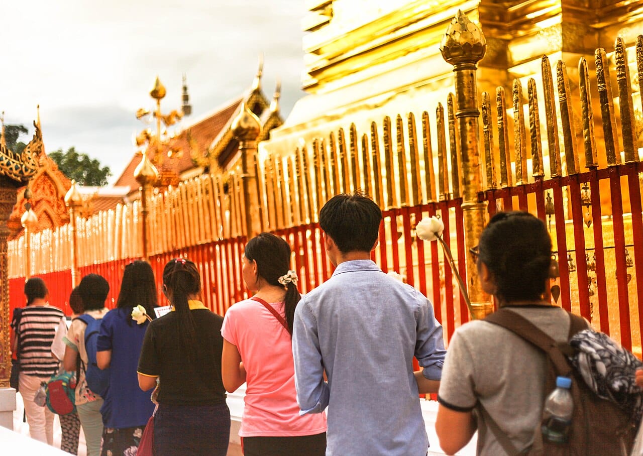 Pilgrims circumambulating the chedi clockwise in the upper terrace, holding lotus flowers