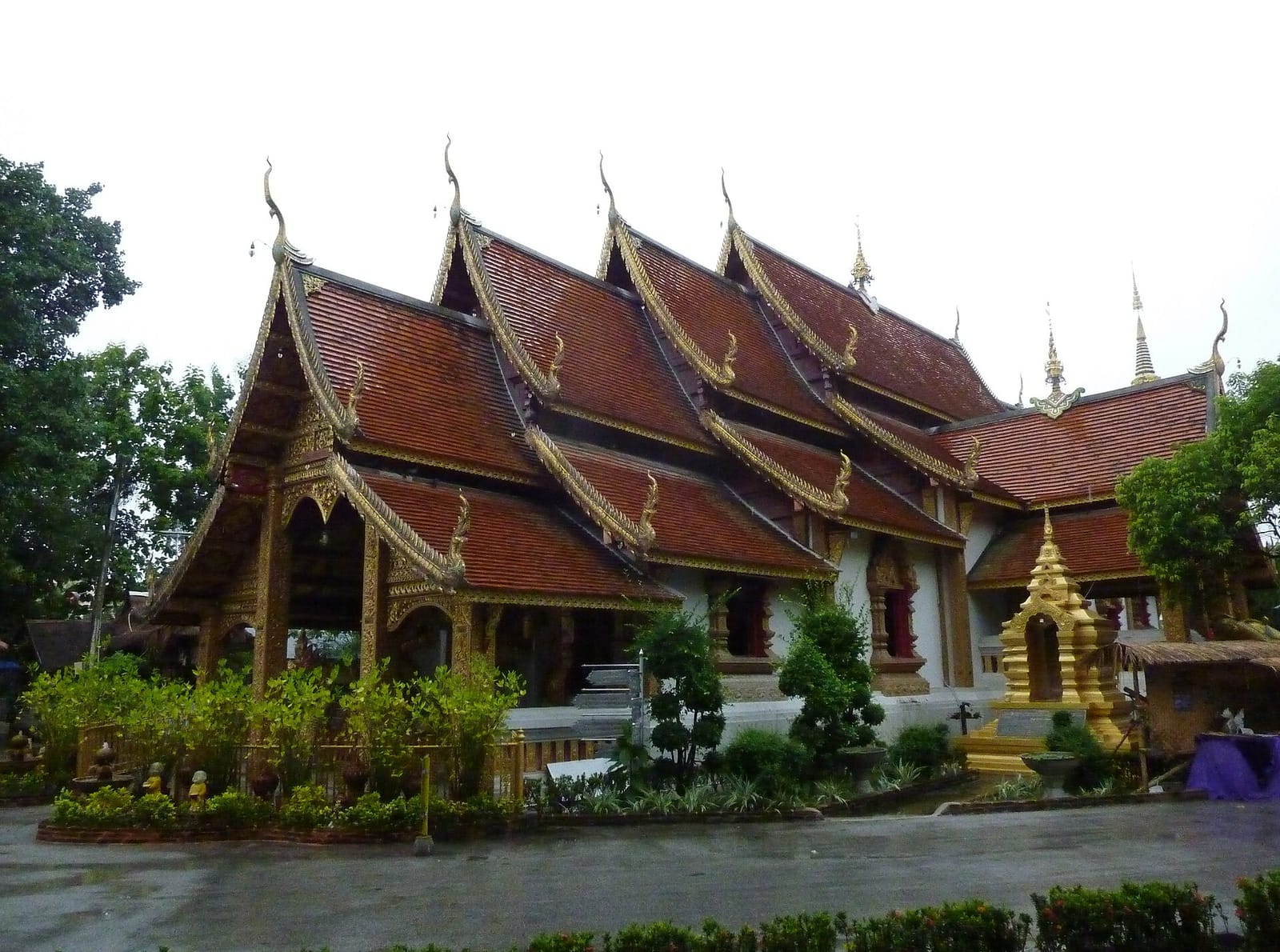 The older Lanna viharn of Wat Sri Suphan next to the silver ubosot, with its tiered red roof, on a rainy day