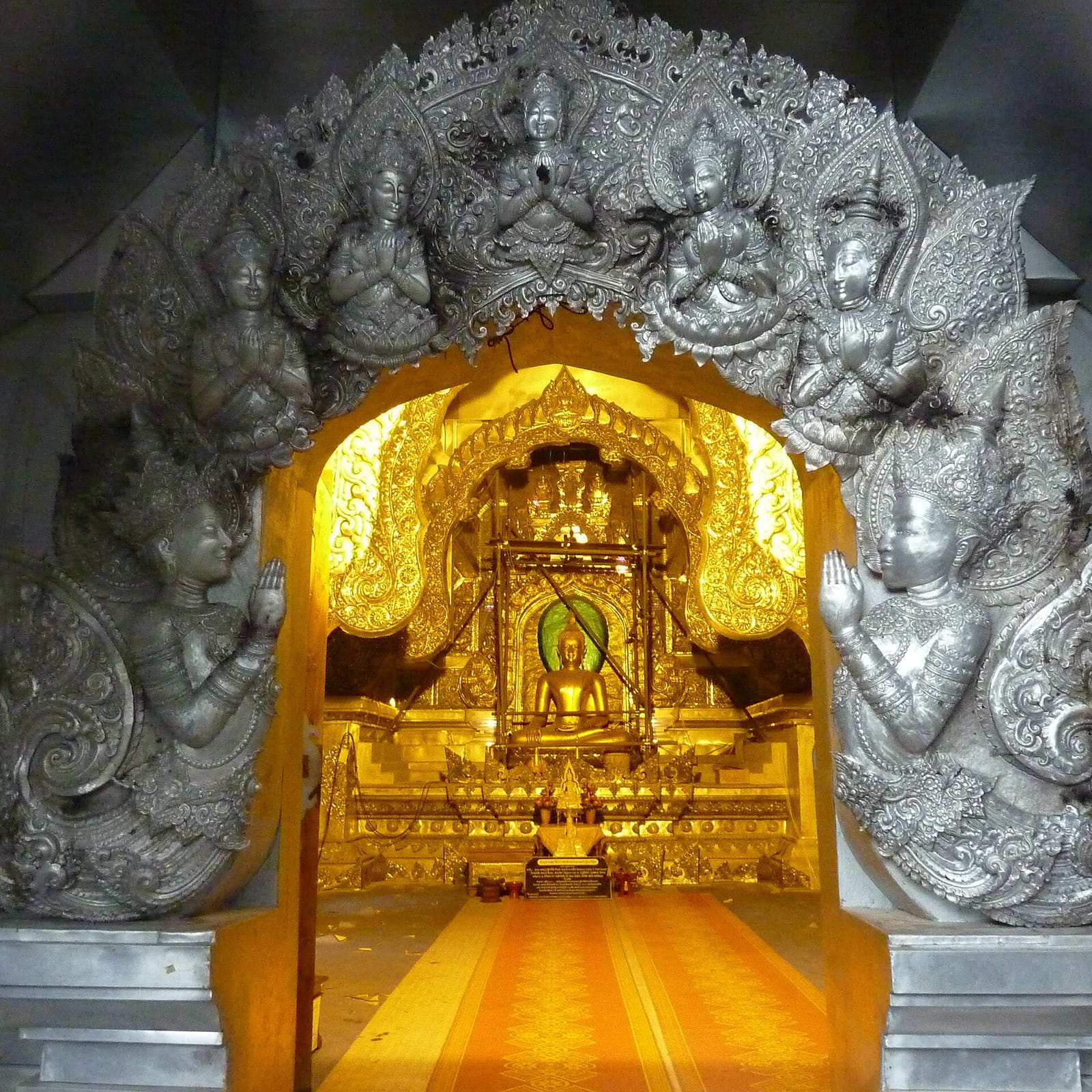 Open doorway of the silver ubosot, with the interior altar visible from outside where women view the hall