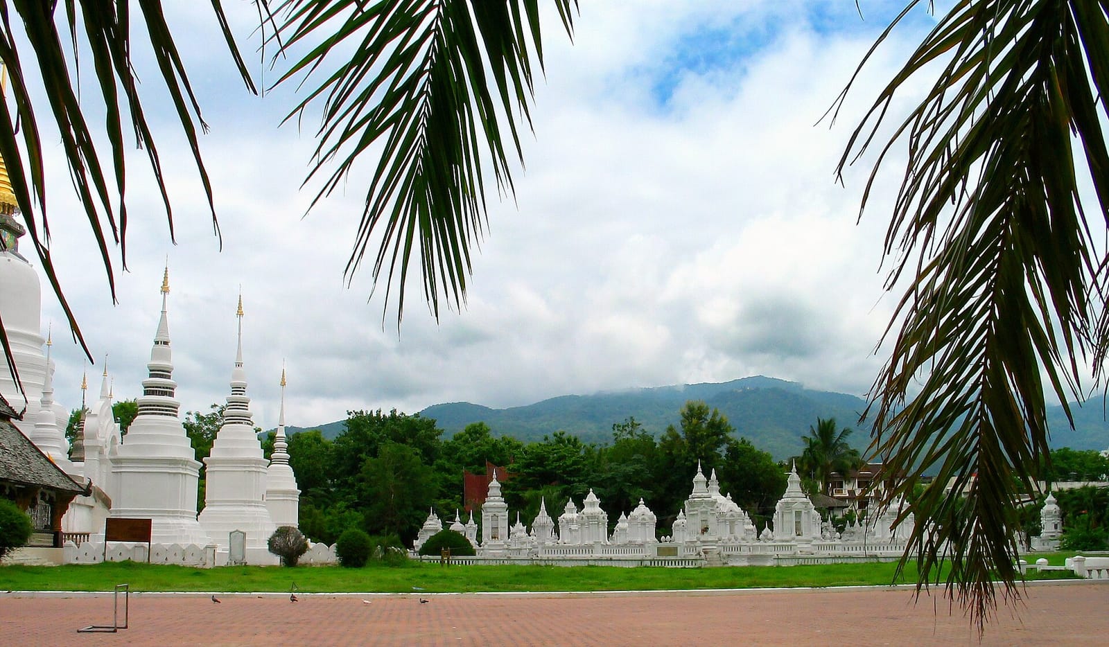 Cluster of small whitewashed royal chedis in the royal cemetery of Wat Suan Dok, with Doi Suthep behind
