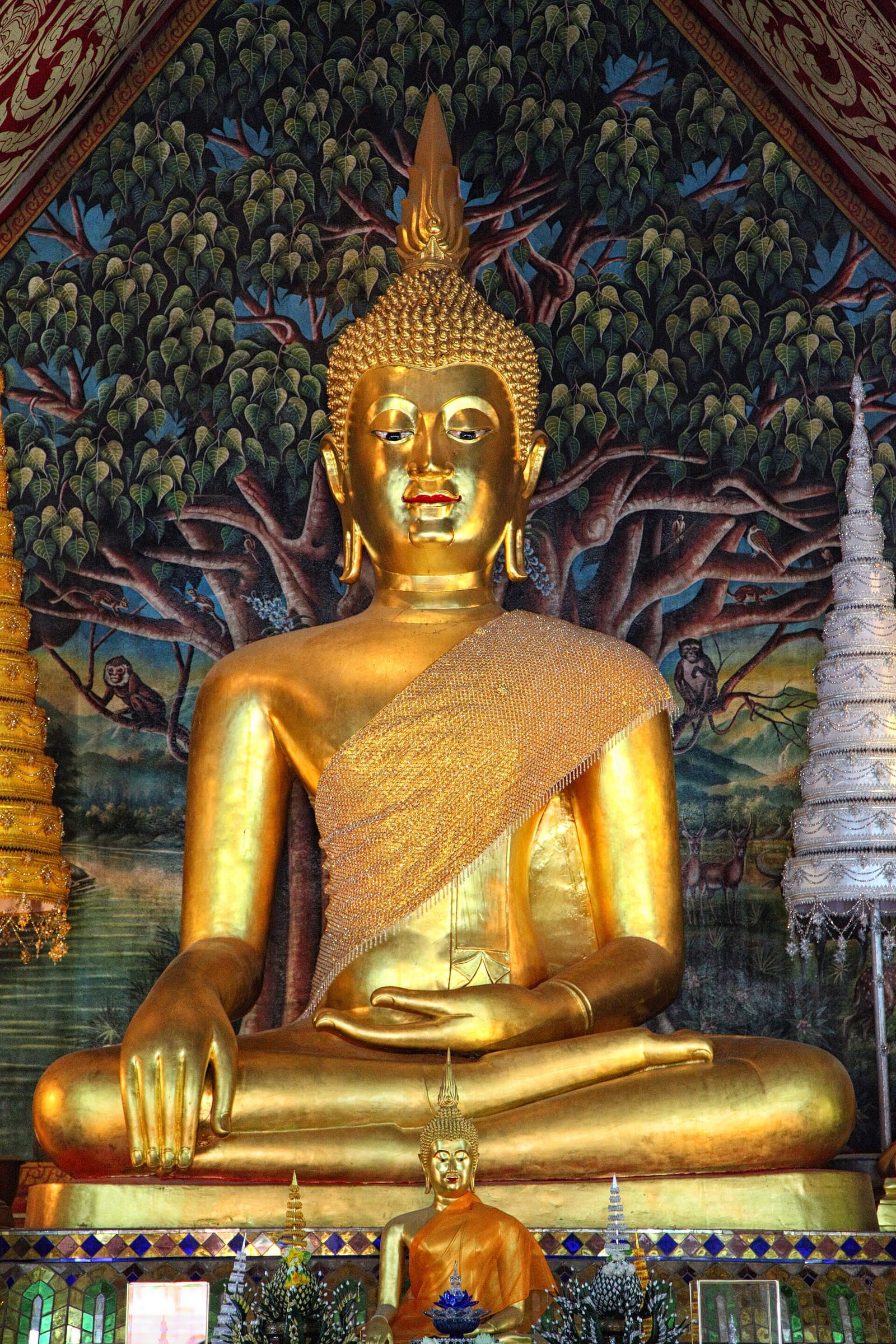 The Phra Chao Kao Tue Buddha image inside the ordination hall of Wat Suan Dok, against a painted Bodhi-tree mural